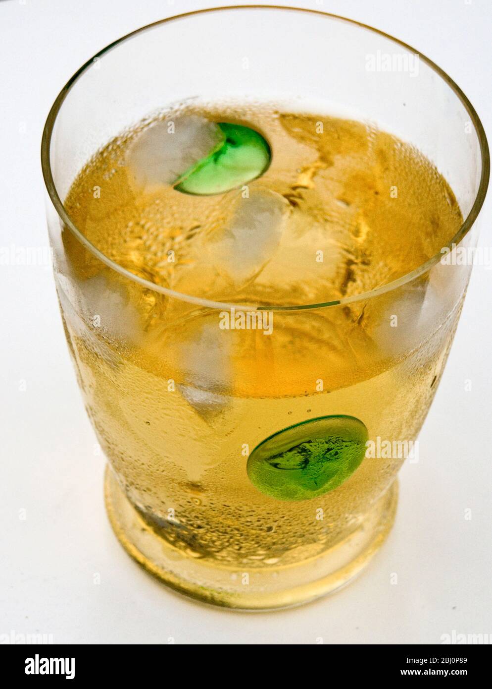 Glass of whisky and soda with ice in thin lead crystal glass with green spots - Stock Photo