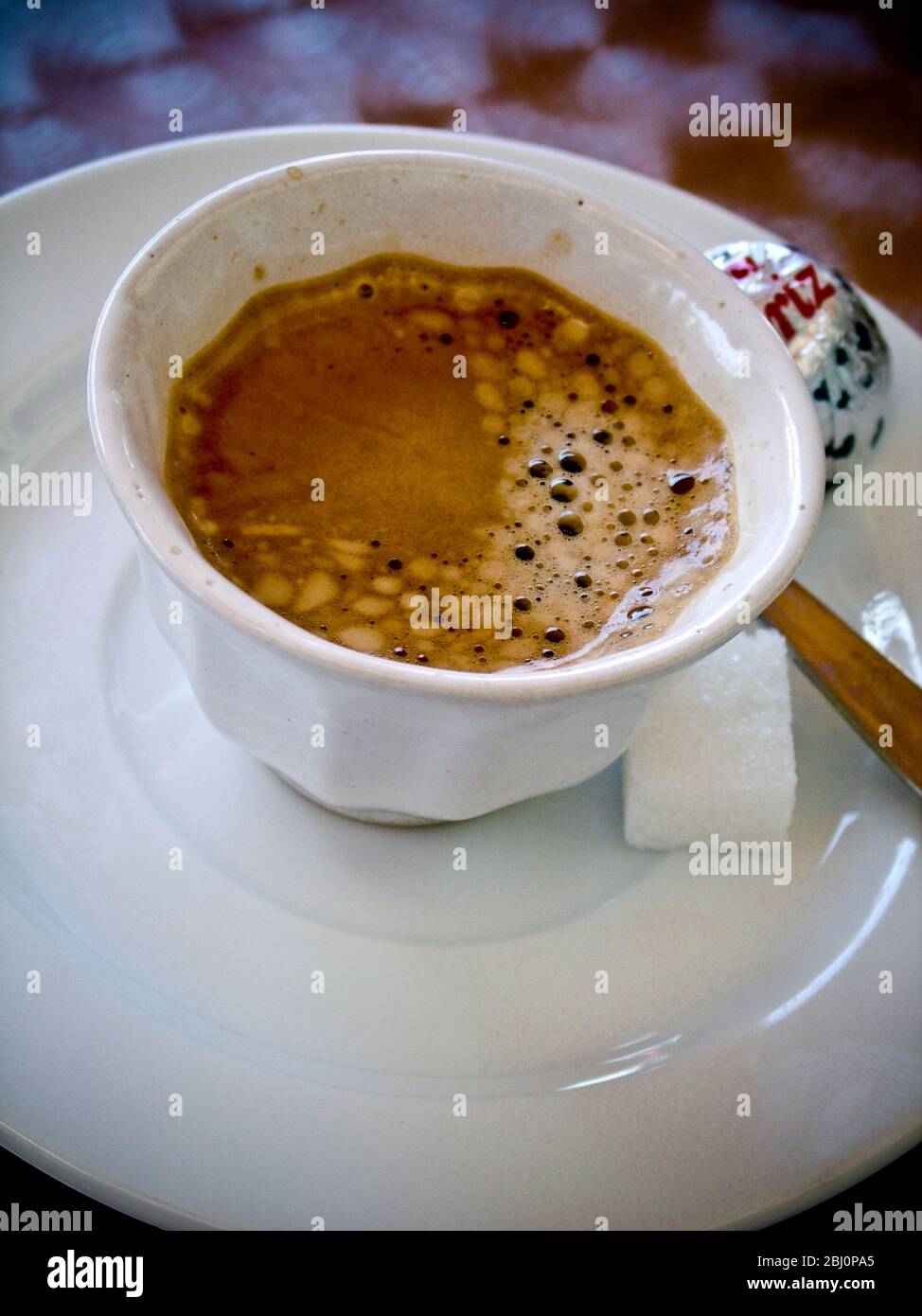 Small handleless cup of strong Turkish coffee on cafe table - Stock Photo