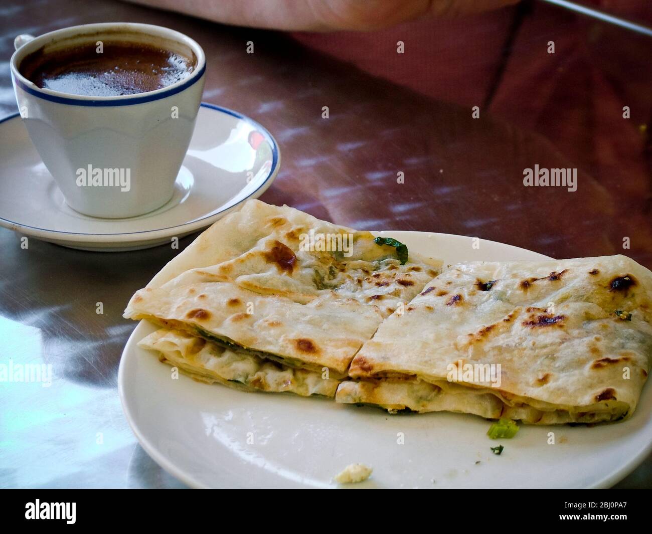 Small cup of strong Turkish coffee with thin savoury filo snack in cafe in resort town of Dalayan, Anatolia, Turkey - Stock Photo