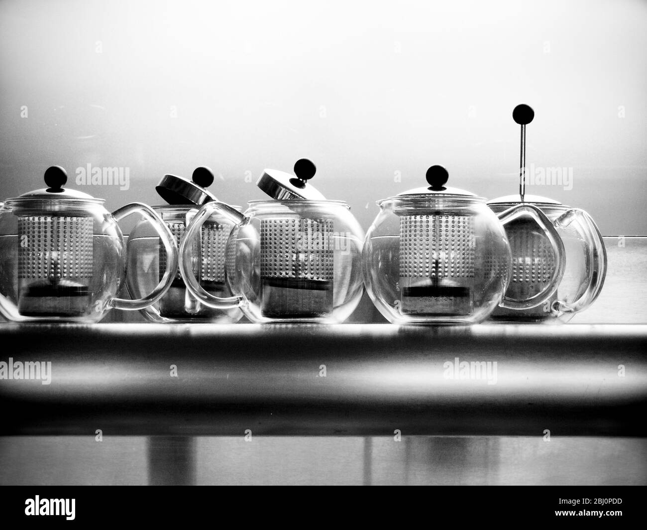 Glass Bodum teapots on metal shelf in restaurant - Stock Photo