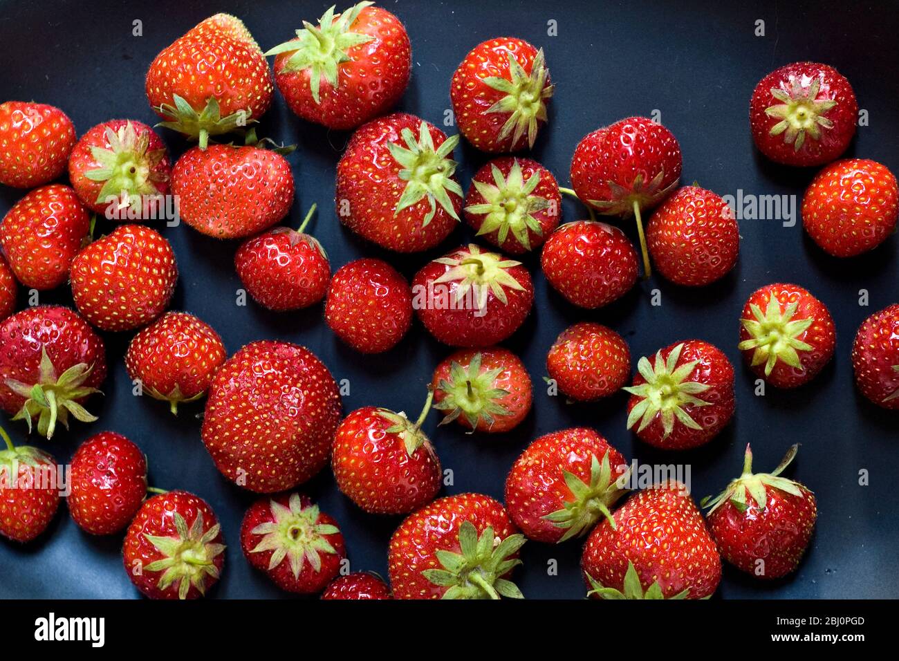 Black plate with red strawberries - Stock Photo