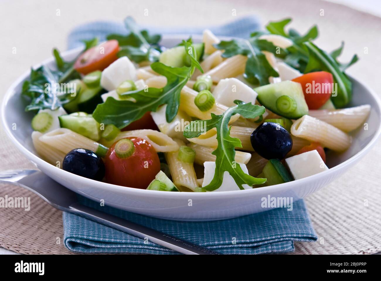 Light, healthy salad of rocket, and mozzarella cubes with penne pasta shapes dresssed in light vinaigrette. Sharper version - Stock Photo