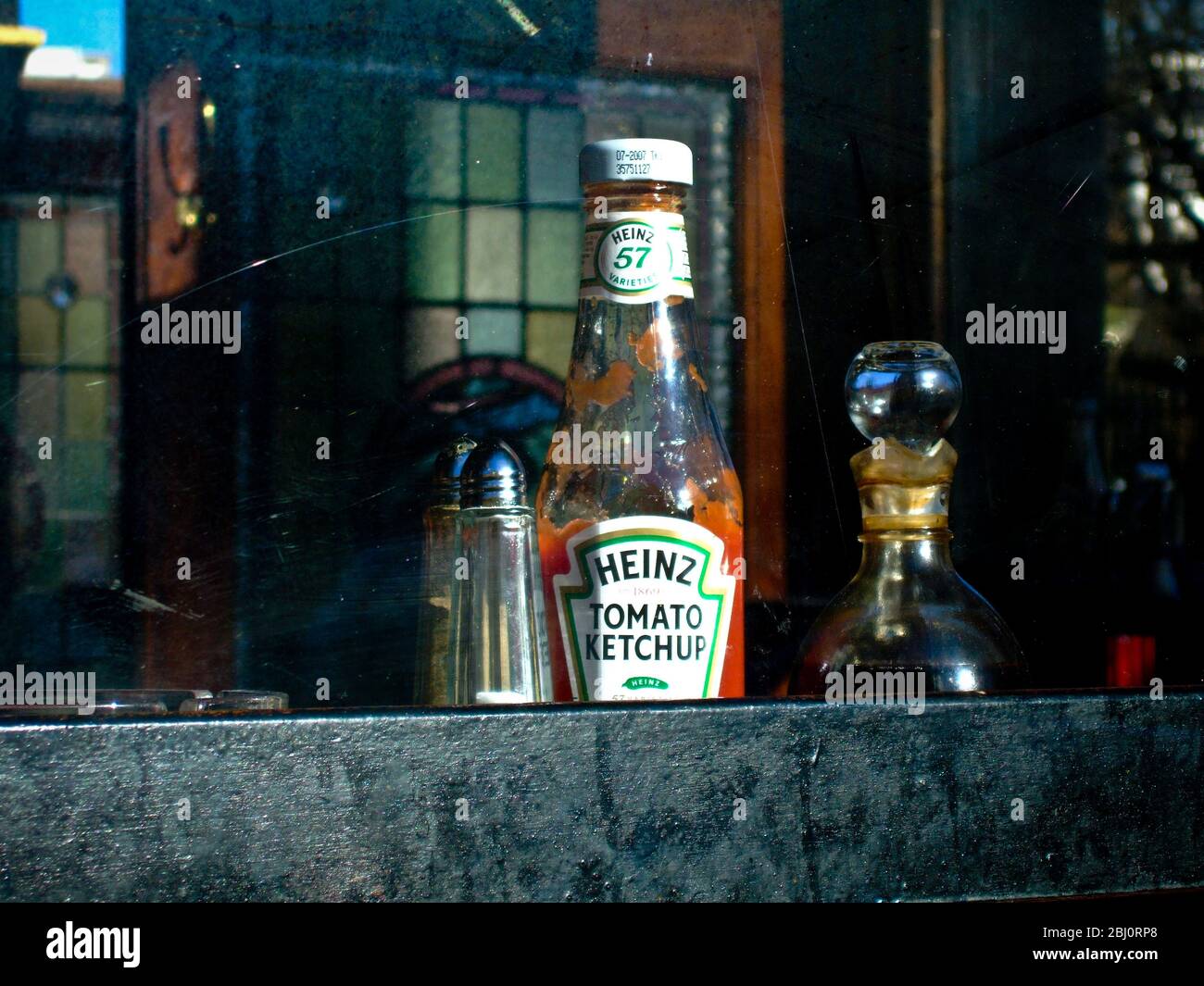 Bottle of Heinz ketchup, salt pot and vinegar bottle on shelf inside window of The Artillery Arms pub in Bunhill Row, London EC1 UK - Stock Photo