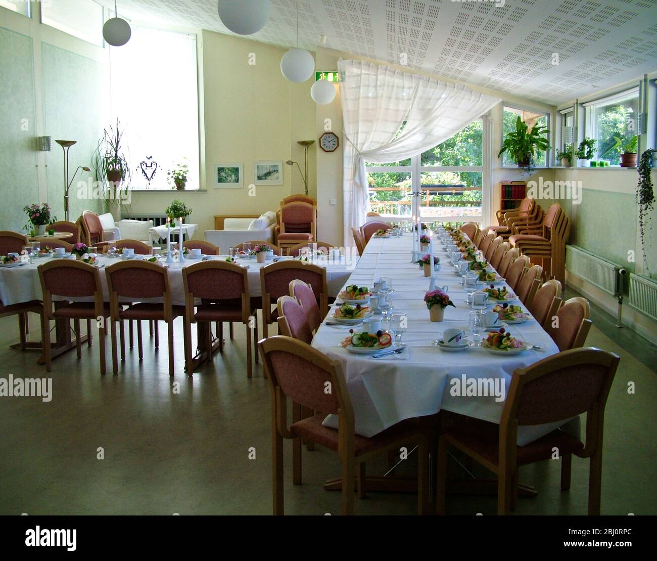 Attractive church hall in Lerum, Sweden, set out for reception lunch after a funeral, with Swedish open sandwiches, candles, and flowers - Stock Photo