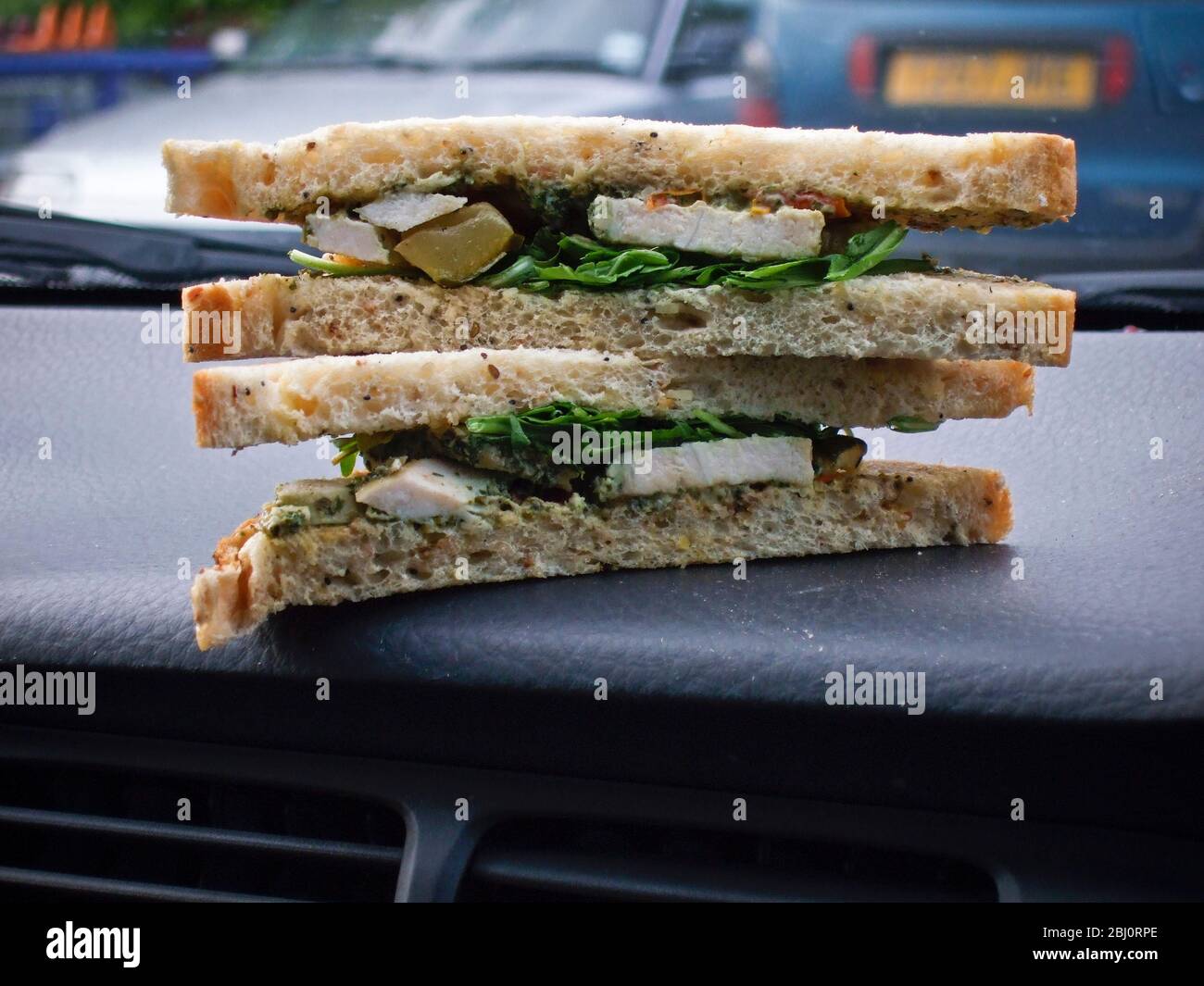Supermarket bought sandwish with chicken and rocket, on dashboard of Volvo in car park - Stock Photo