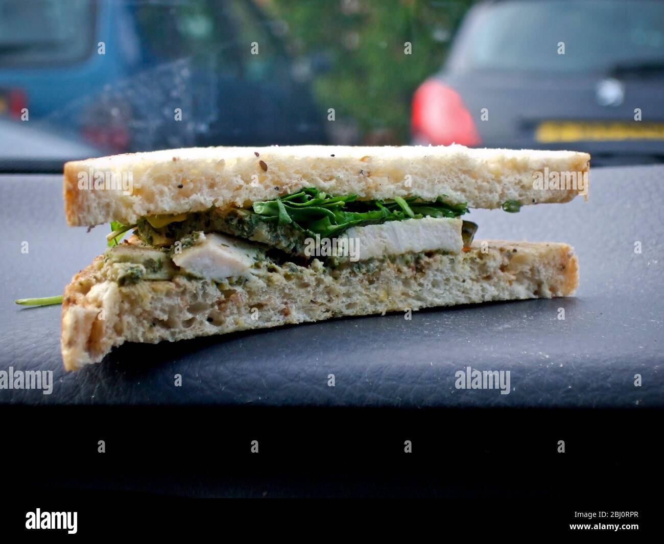 Supermarket bought sandwish with chicken and rocket, on dashboard of Volvo in car park - Stock Photo