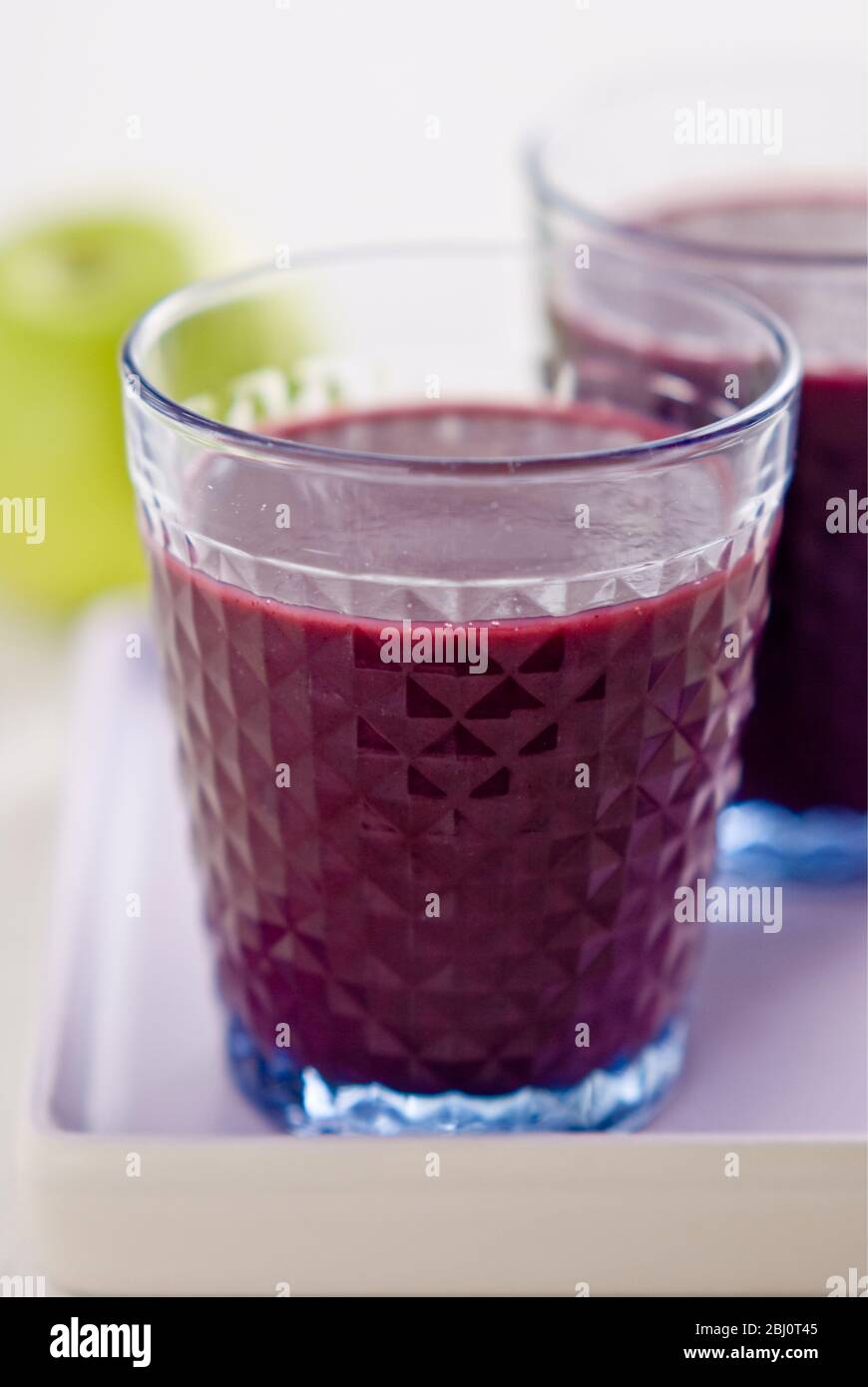 Healthy snack of freshly made blackcurrant and raspberry smoothie with fresh green apple - Stock Photo
