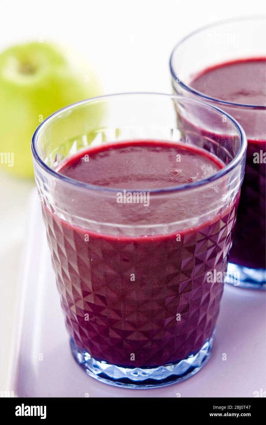 Healthy snack of freshly made blackcurrant and raspberry smoothie with fresh green apple - Stock Photo