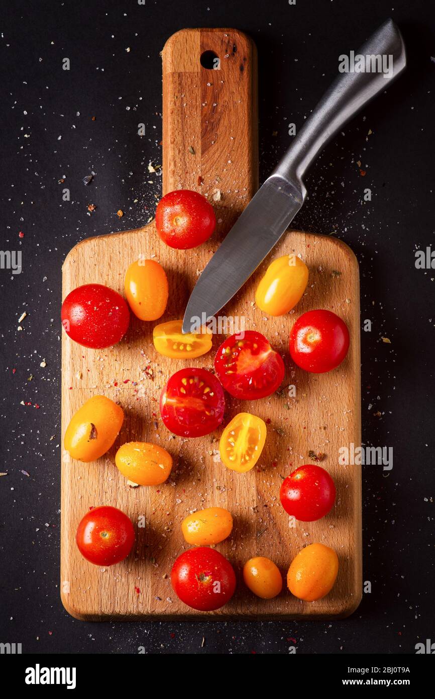 Different tomatoes cultivars on a wooden board on the black background. Multicolor tomatoes Stock Photo