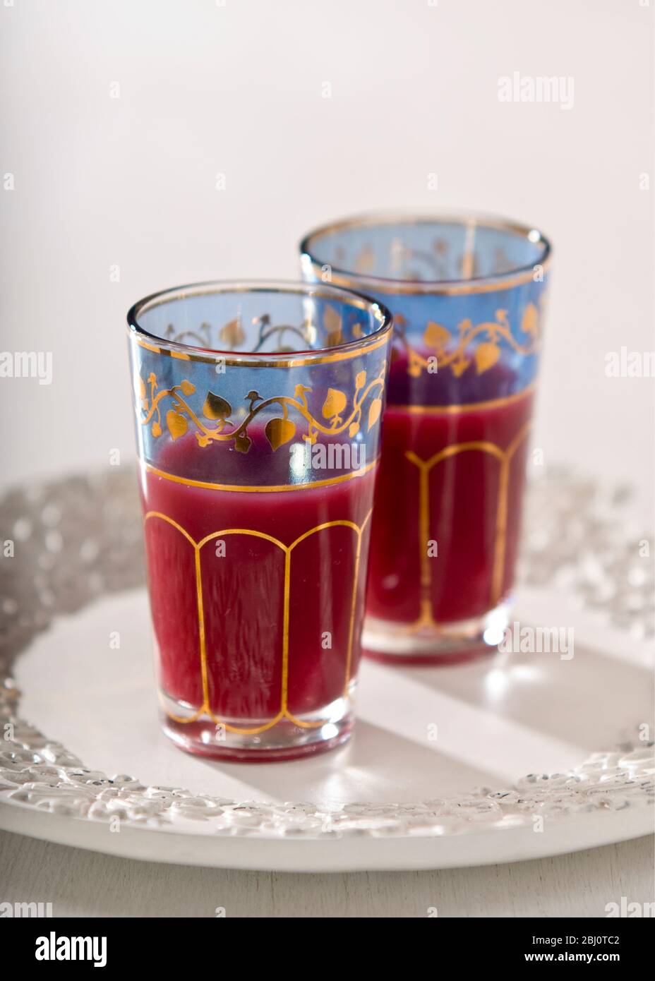 Pomegranate juice in ornate middle eastern tea glasses - Stock Photo