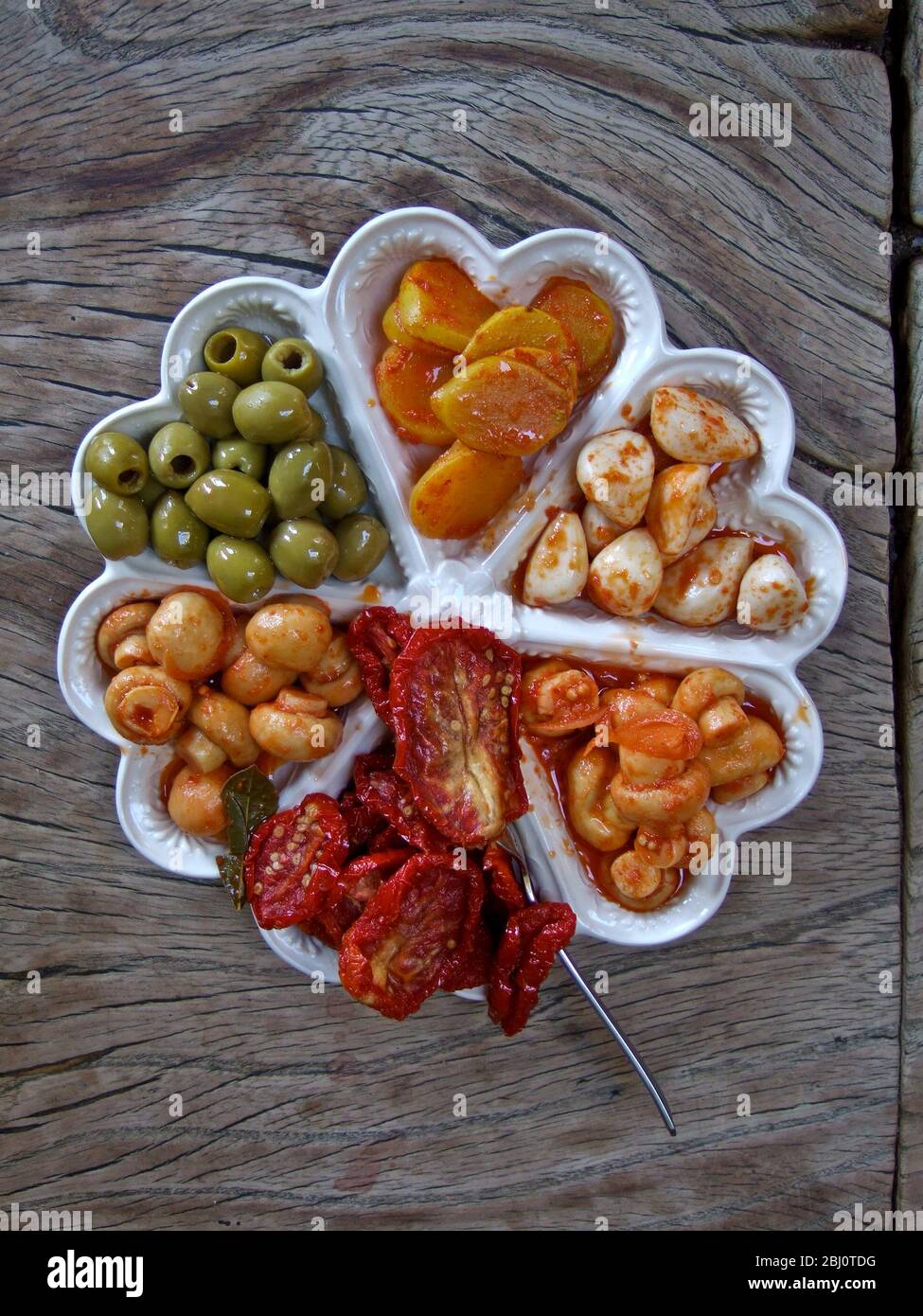 Pretty decorative dish with heart shaped compartments with preserved and pickled vegetables, as hors d'ouevres. - Stock Photo