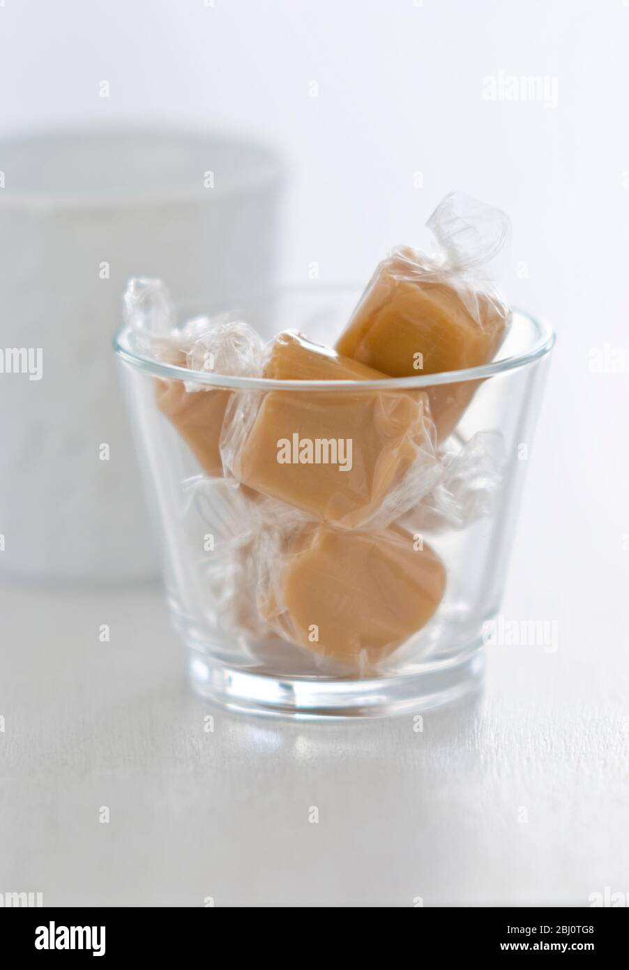 A few toffees wrapped in cellophane in a glass pot - Stock Photo