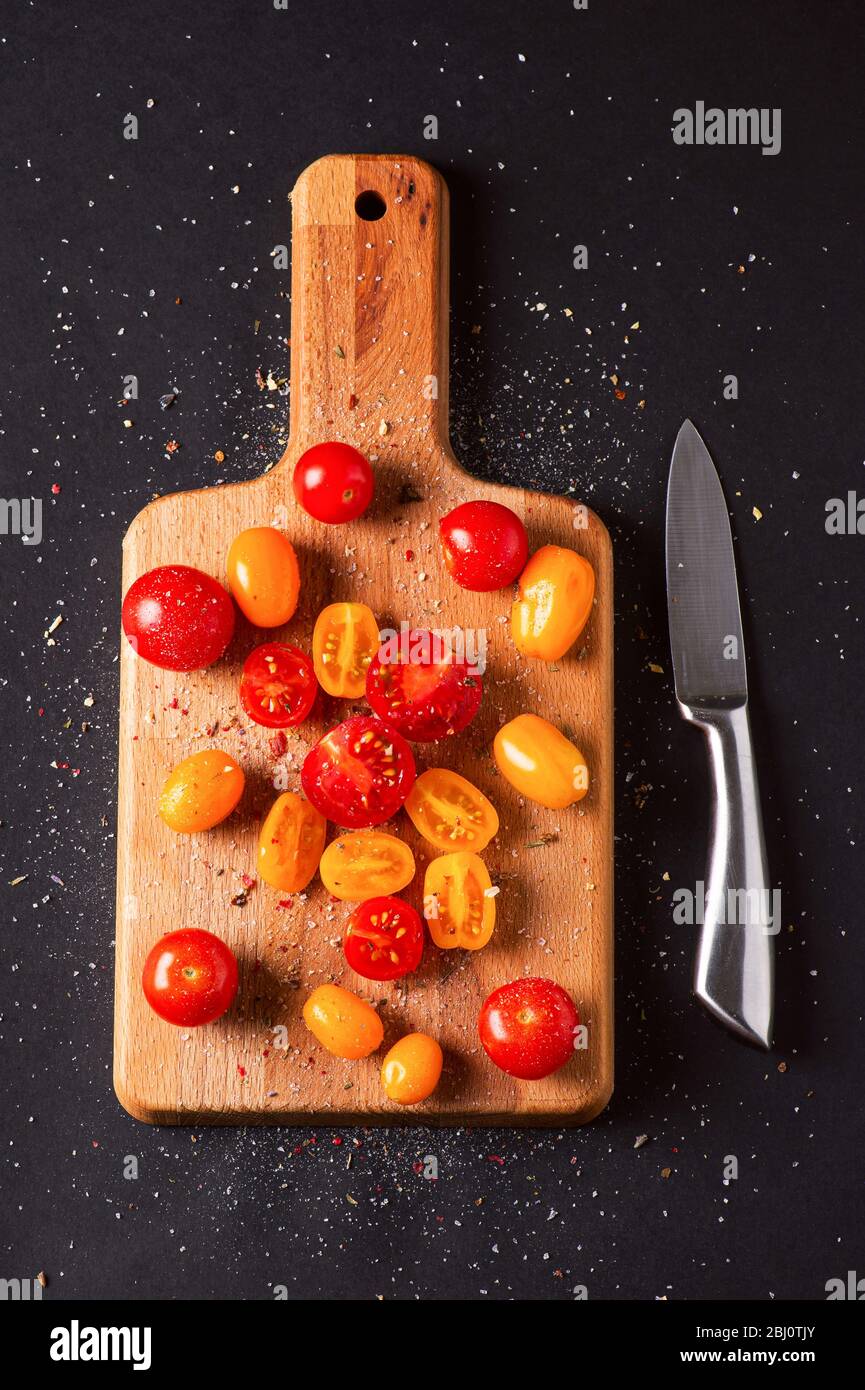 Different tomatoes cultivars on a wooden board on the black background. Multicolor tomatoes Stock Photo