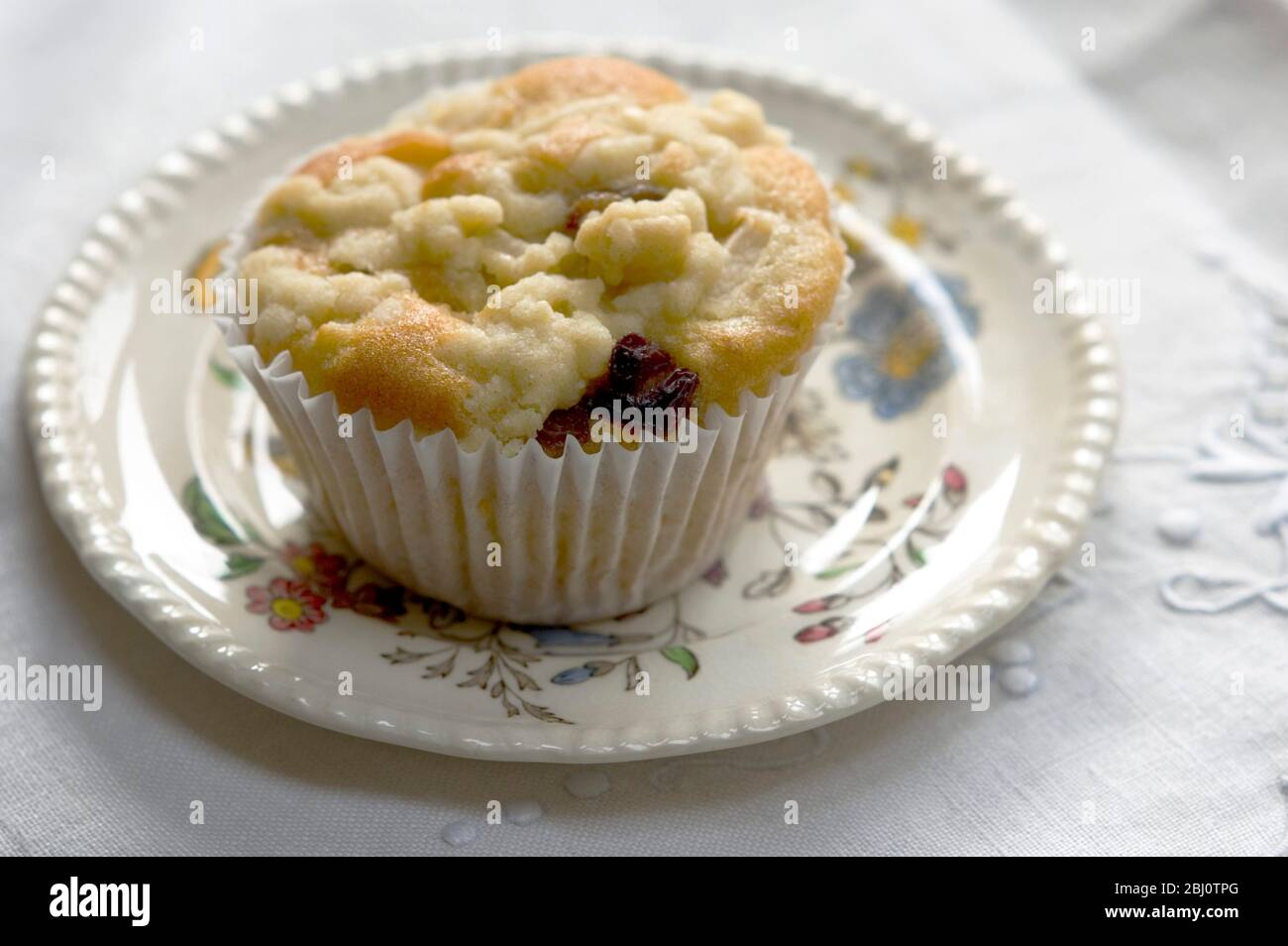 Muffin baked with topping of fresh grated apple on small patterned plate - Stock Photo