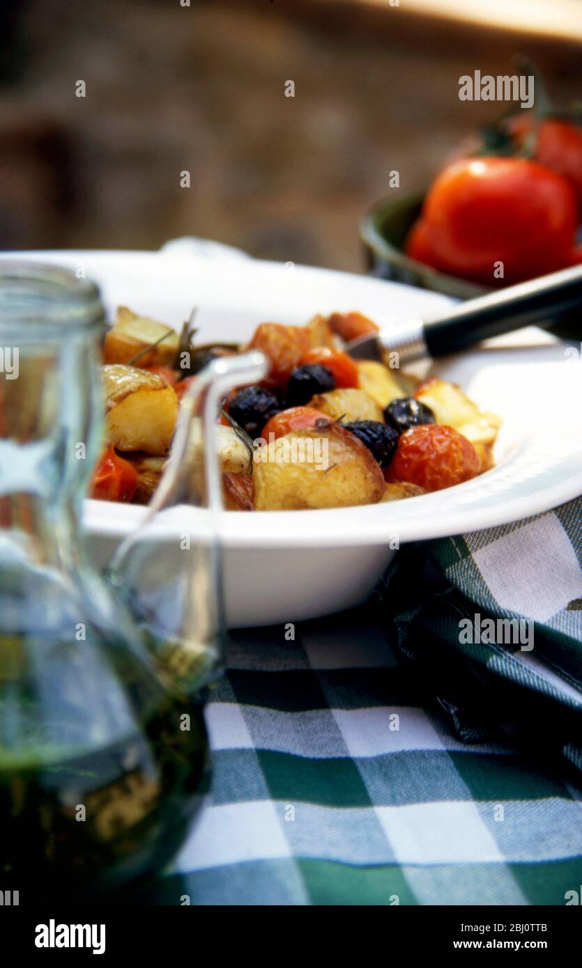 White bowl of roasted vegetables - potatoes, tomatoes, olives with rosemary and garlic and olive oil - Stock Photo