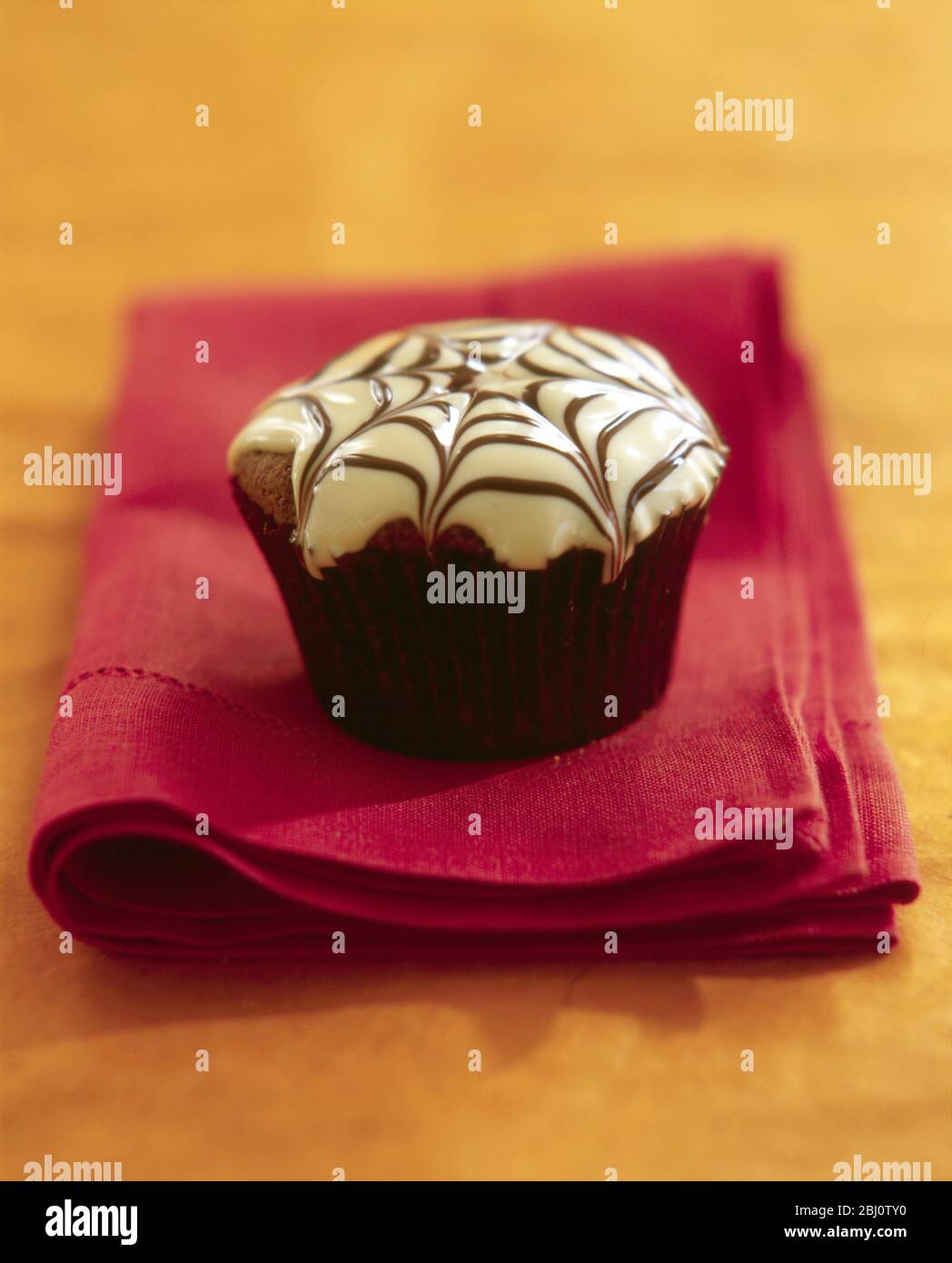 Muffin decorated with spider's web in icing for Hallowe'en - Stock Photo