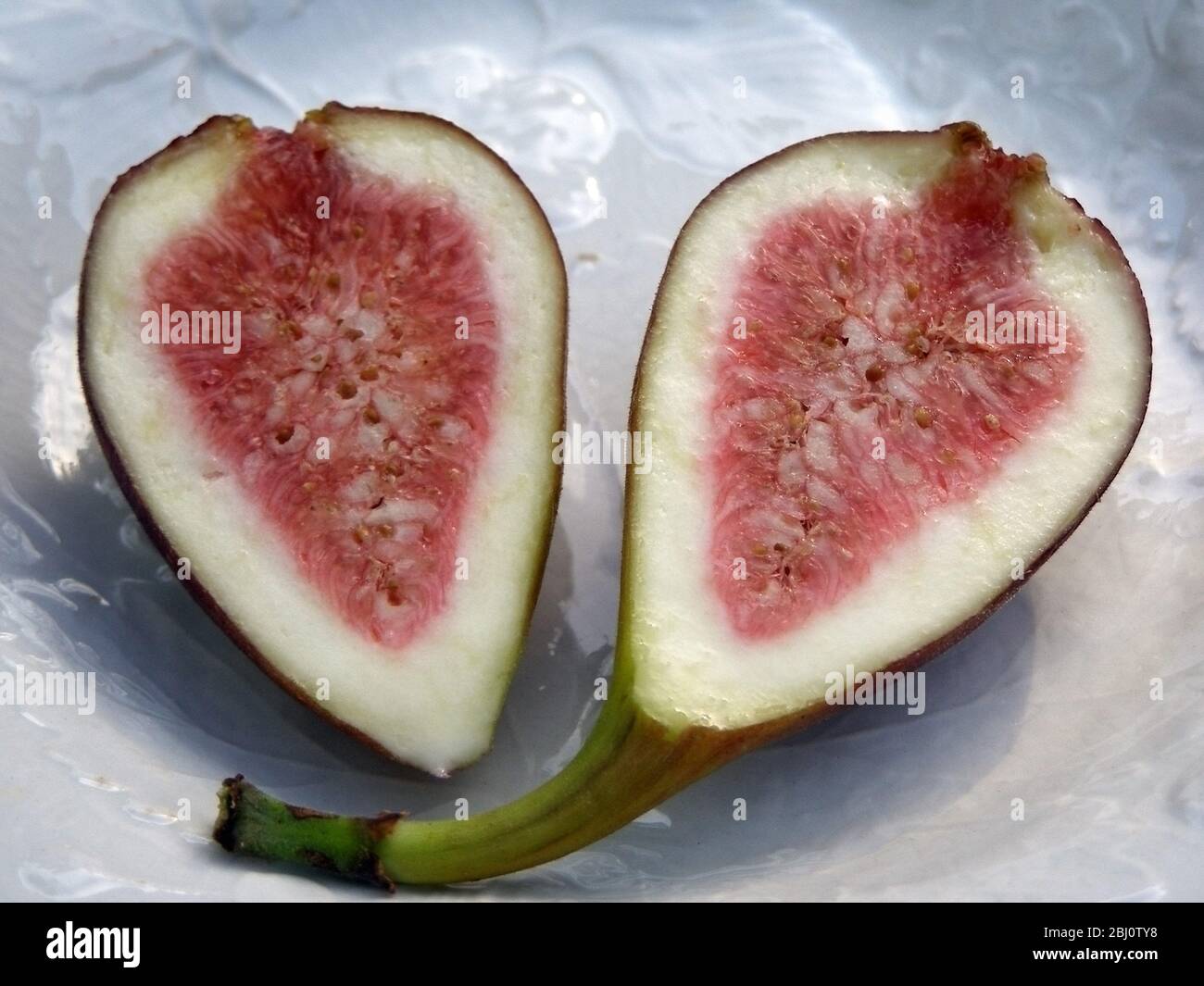 Halved ripe fig on white plate - Stock Photo