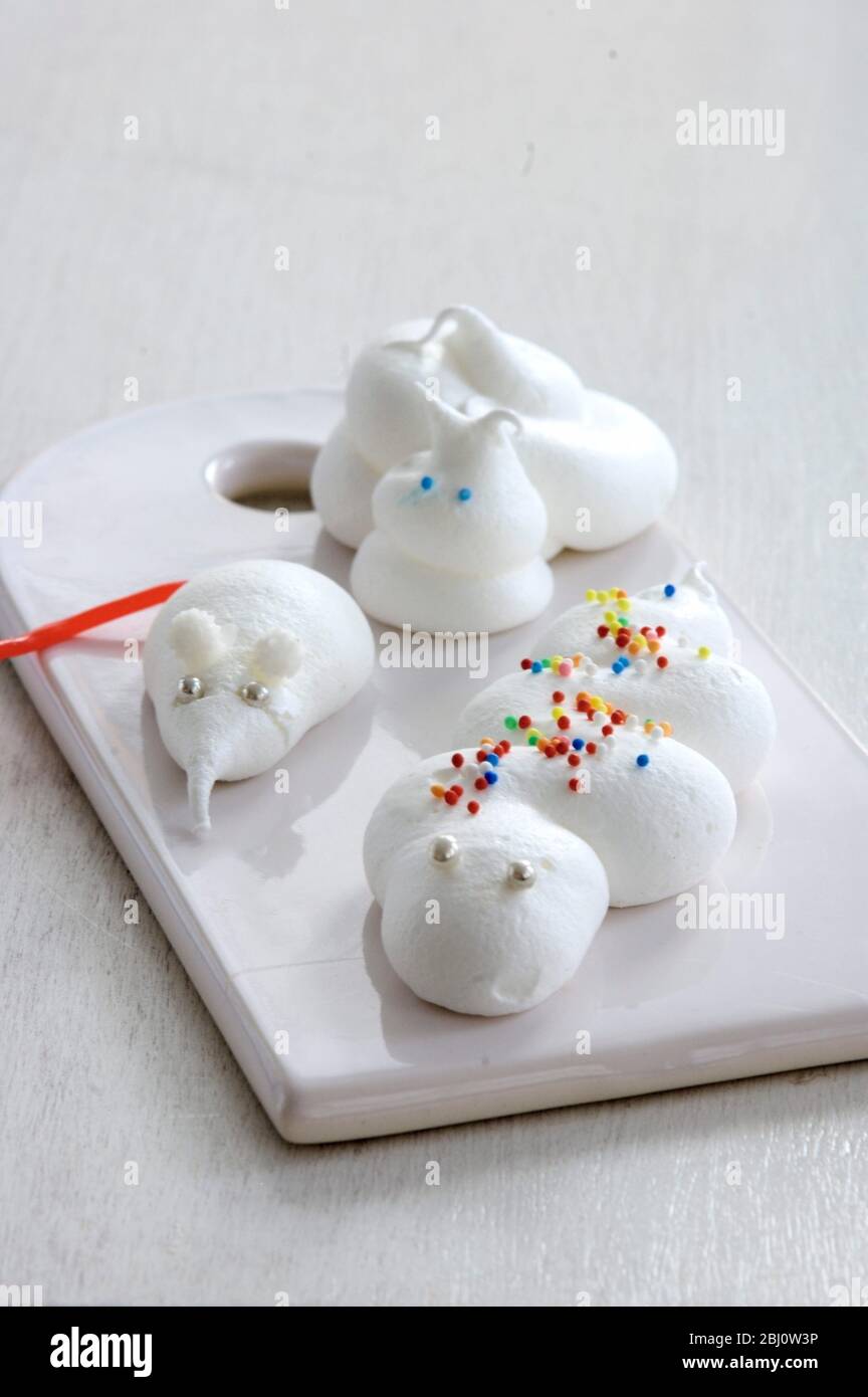 Imaginative creatures including snail, and serpent, and a little mouse or shrew made of meringue on white porcelain board - Stock Photo