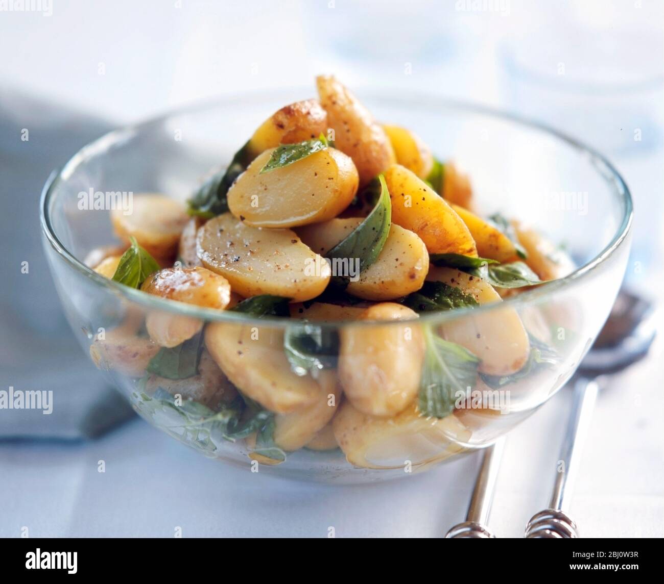 Halved, baby new potatoes cooked in their skins, dressed with vinaigrette with whole grain mustard and black pepper, and sprinkled with mint leaves - Stock Photo
