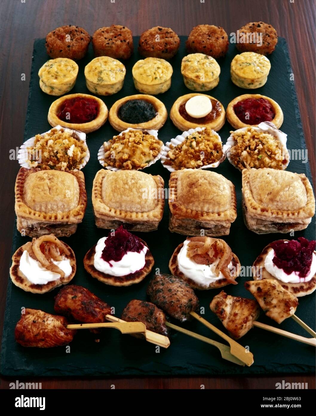 Selection of party foods and savouries on black slate background - Stock Photo