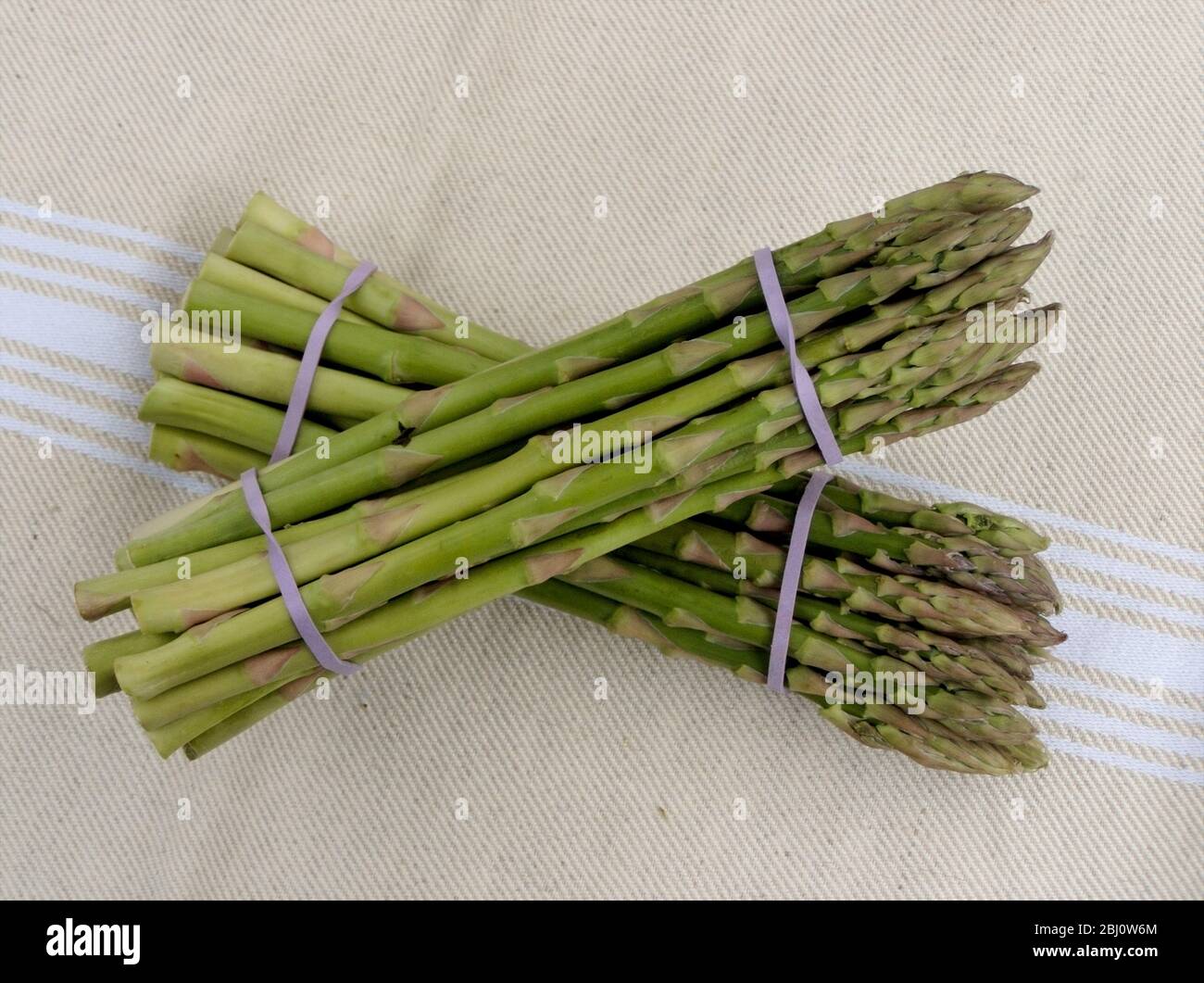 Two bunches of asparagus on natural cloth - Stock Photo