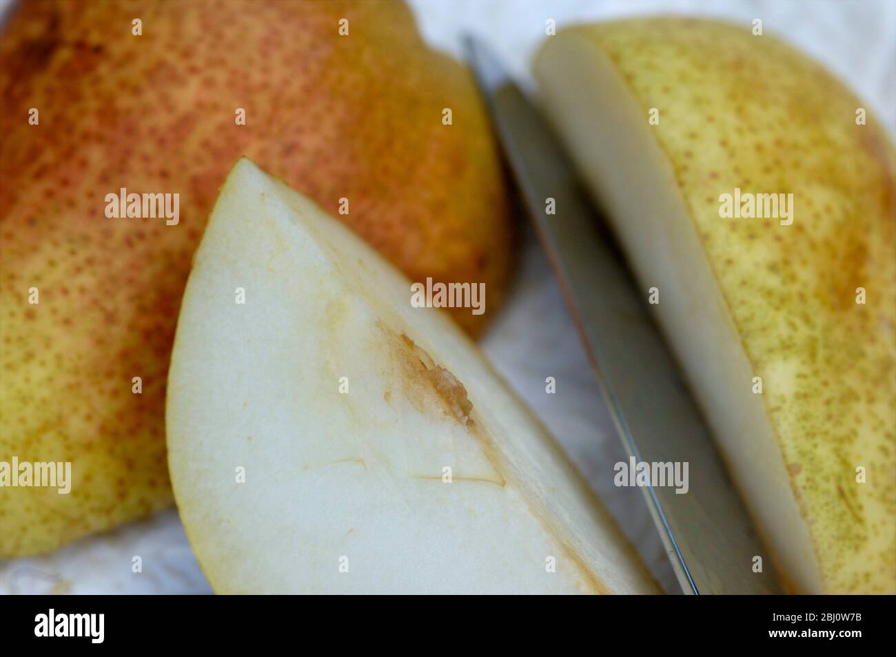 Close up of cut pear and knife on white plate - Stock Photo