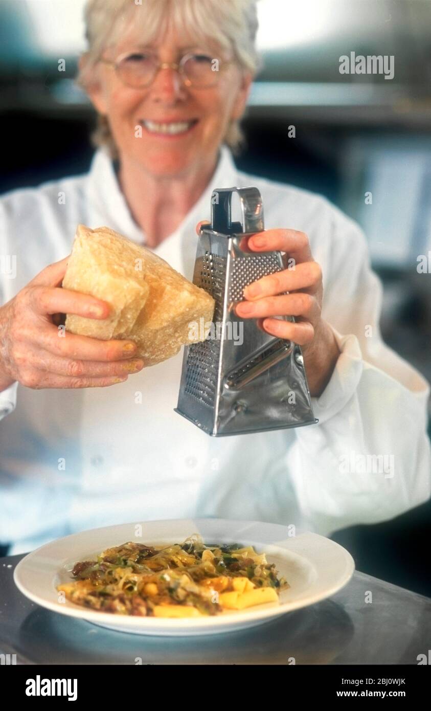 Chef Rose Gray of London's RIver Cafe restaurant grating parmesan over dish of papardelle with wild mushrooms - Stock Photo