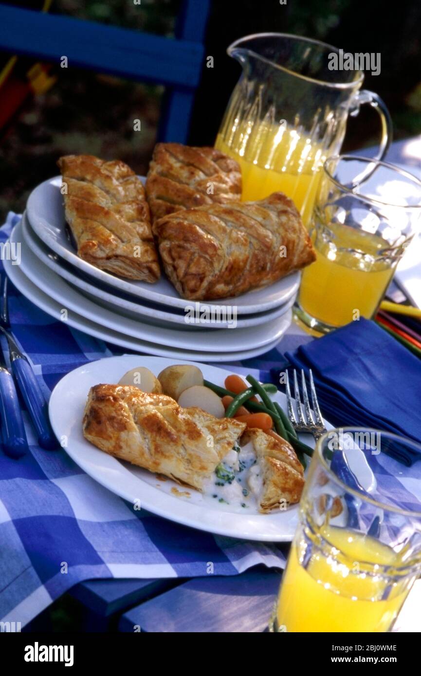Light lunch served outdoors of puff pastry wrapped fish in cheese sauce with broccoli - Stock Photo