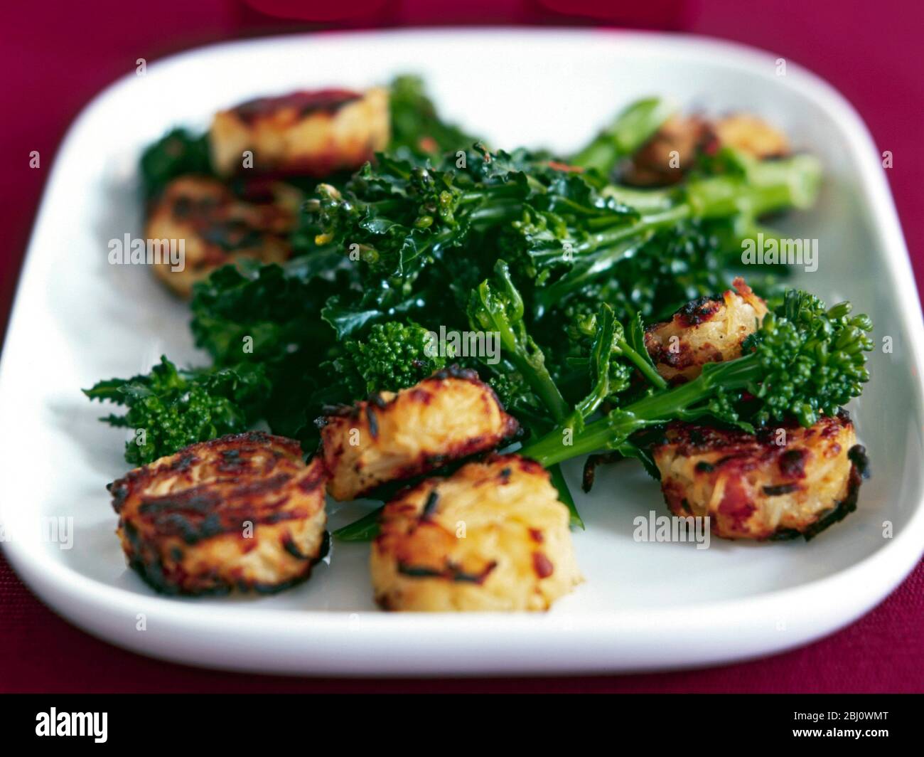 Vegetable dish of sprouting broccoli spears served with rosti potato cakes - Stock Photo