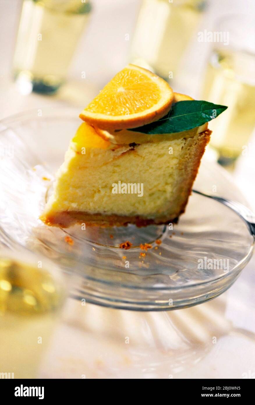 Piece of orange cheesecake on stack of glass plates - Stock Photo
