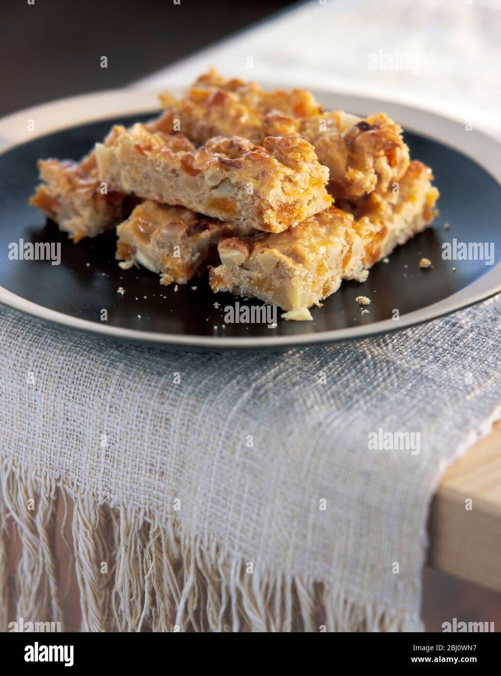 Home made flapjacks stacked on brown plate - Stock Photo