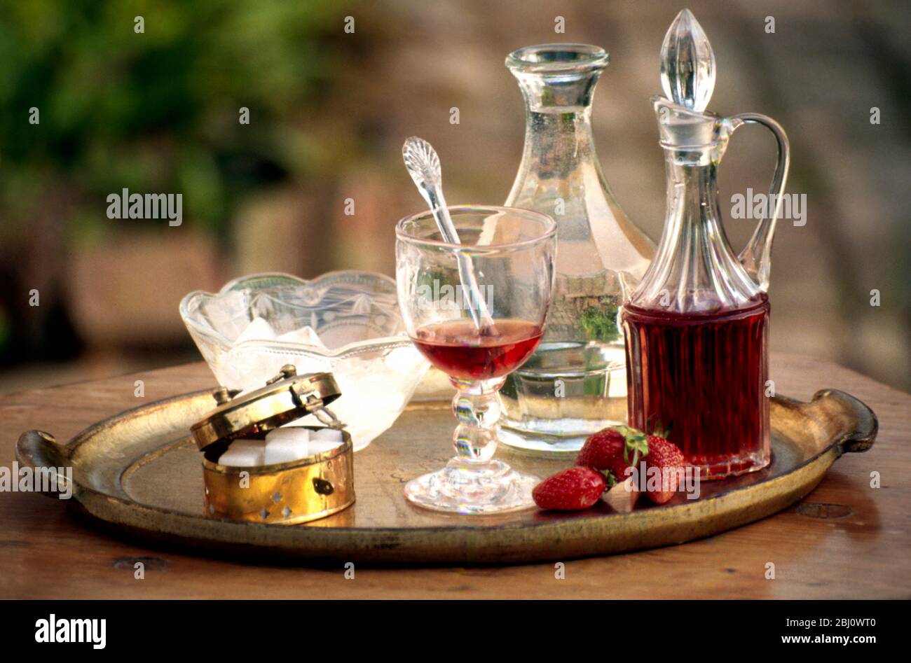 Making up a strawberry cordial using old glassware on florentine gilt tray - Stock Photo