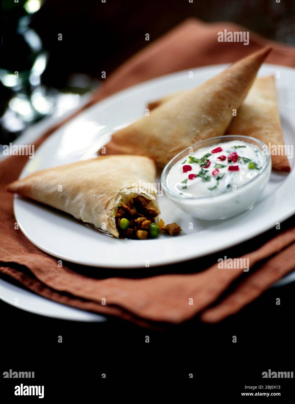 Samosas stuffed with curried quorn with yoghurt dressing - Stock Photo