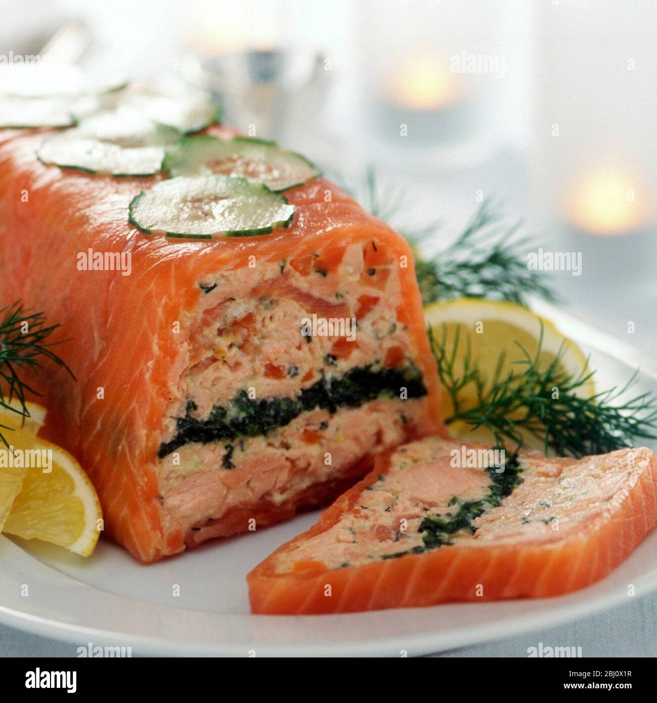 Cold smoked and fresh salmon terrine layered with spinach, served with lemon wedges and dill sprigs - Stock Photo