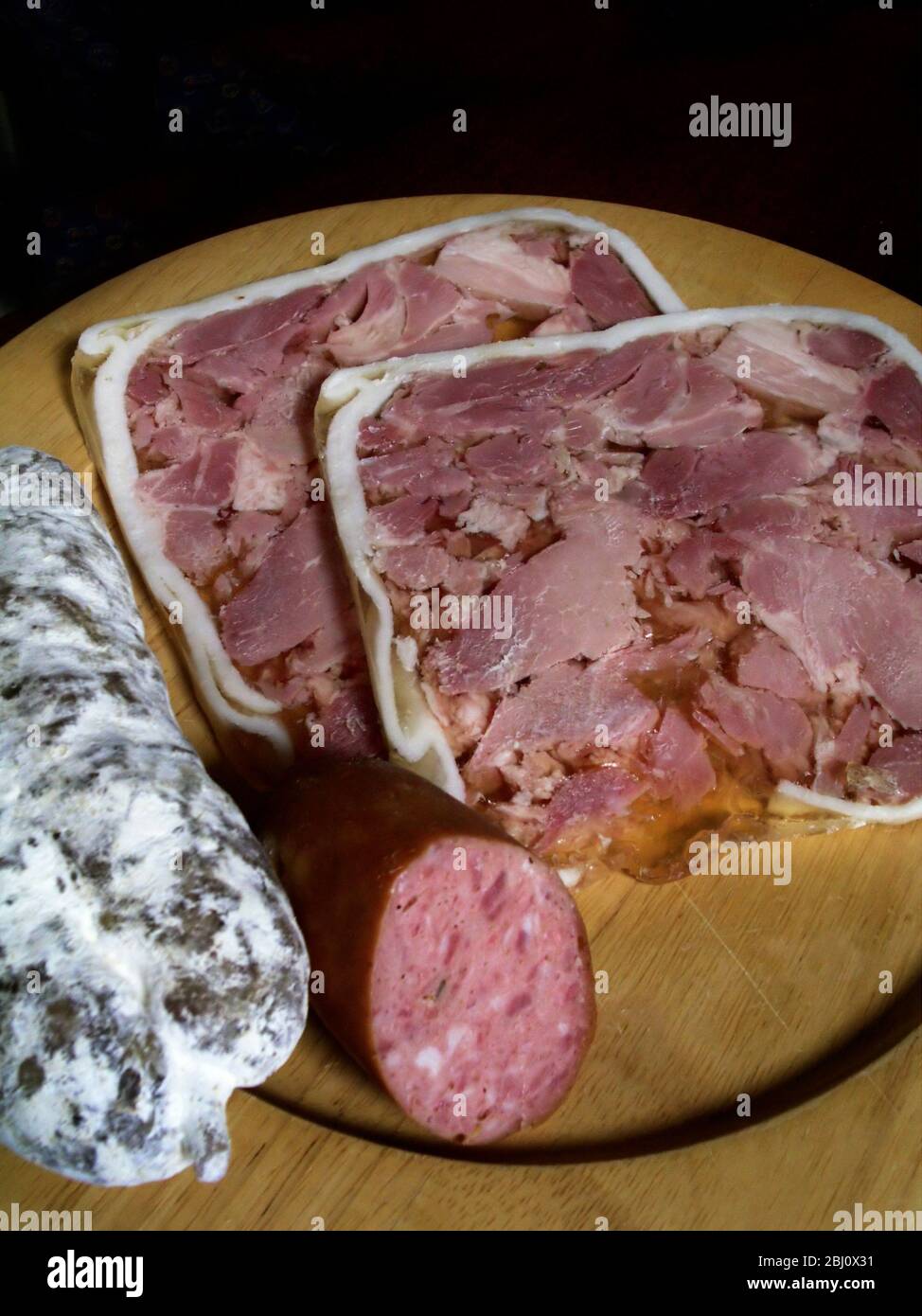 Wooden plate of French charcuterie, saucisson, and tete de veau - Stock Photo