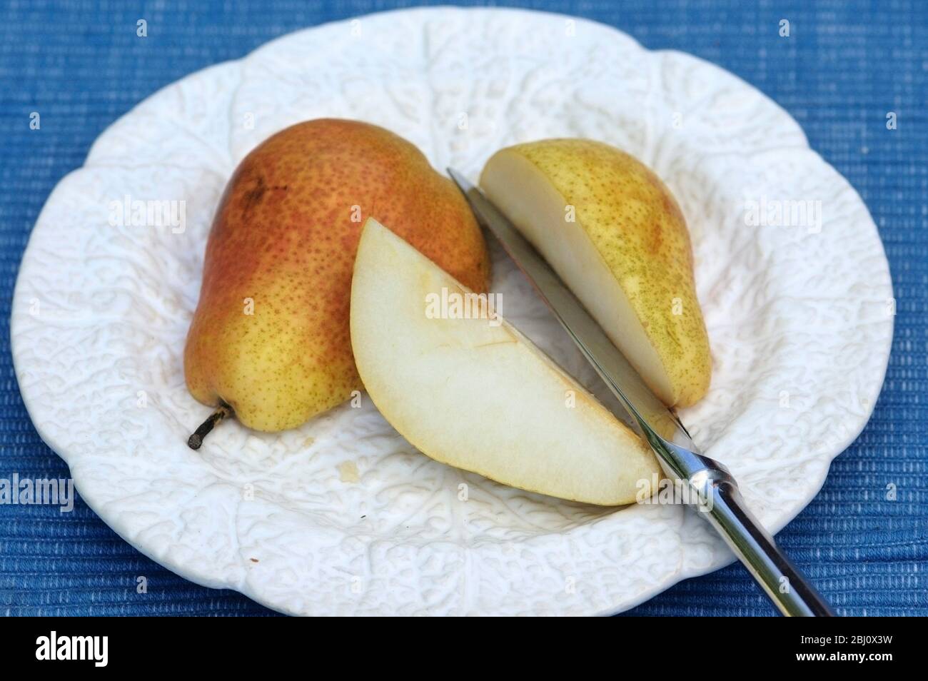Pear on white cabbage leaf plate with fruit knife - Stock Photo