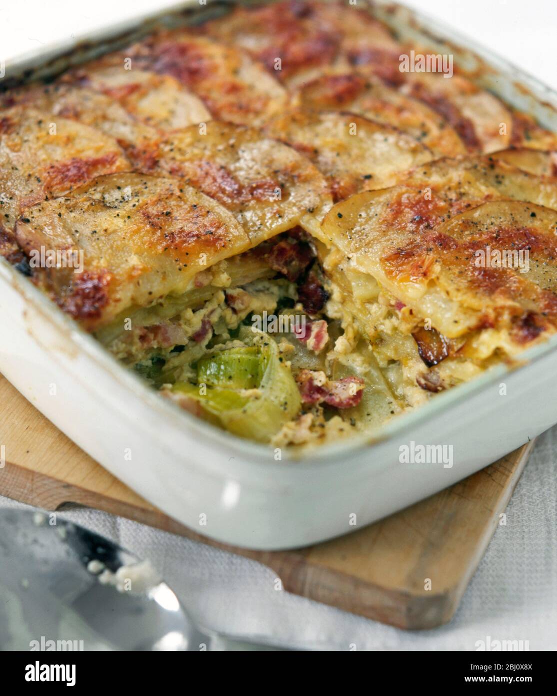 leek bacon and potato gratin baked in large square white ceramic bakinh