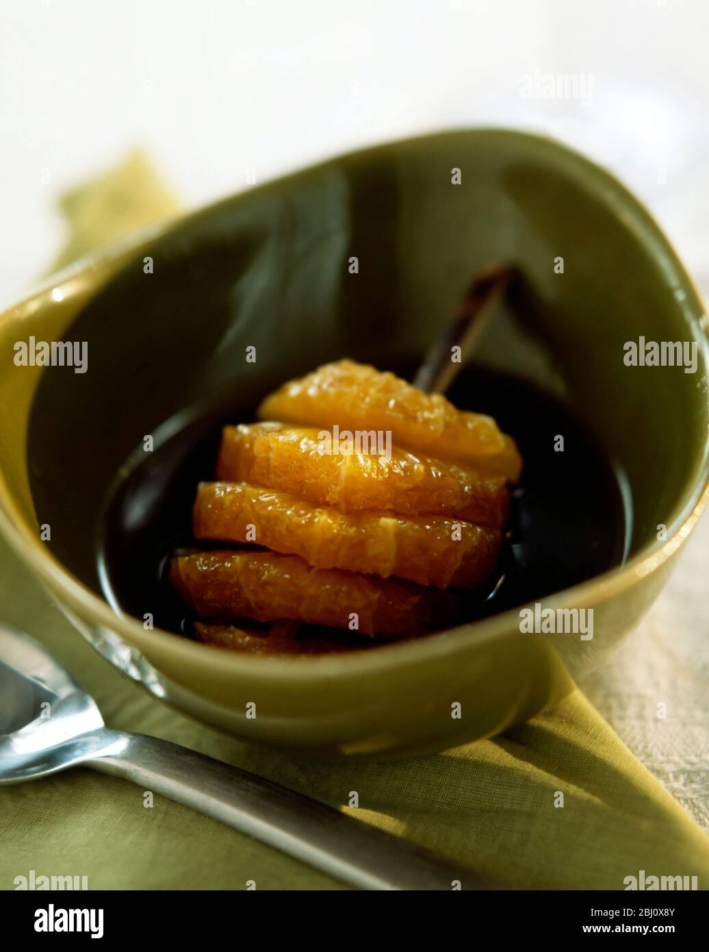 Dessert of orange slices in green bowl in their juice - Stock Photo