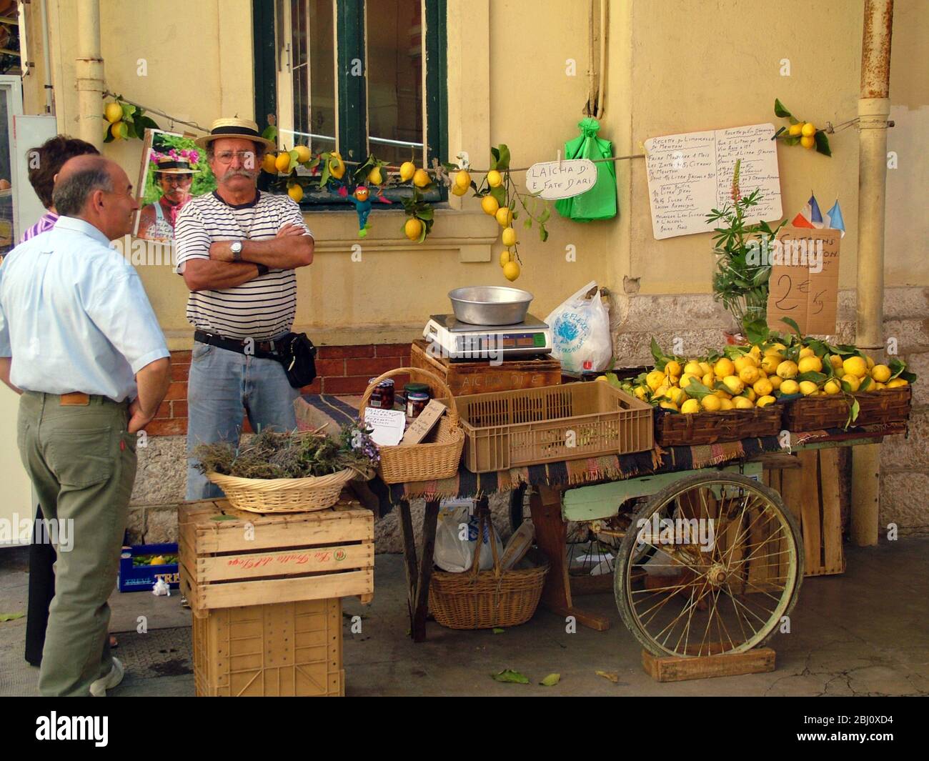 Colourful market trader selling lavender and lemons, in Menton, south of France - Stock Photo