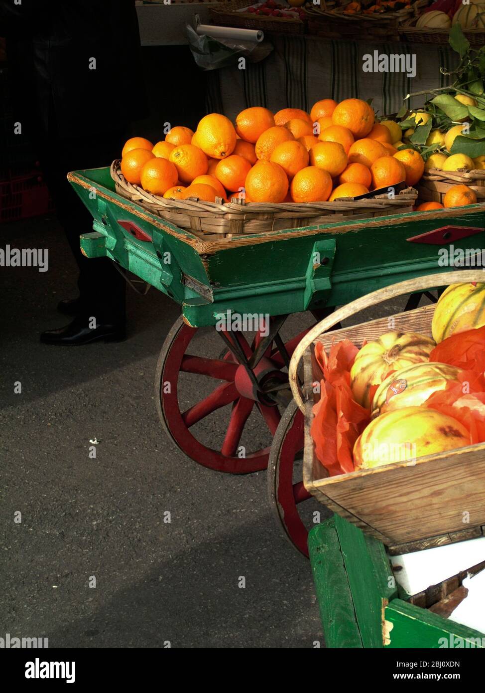 Green and red painted market handcart full of oranges in the market at Menton, south of France - Stock Photo