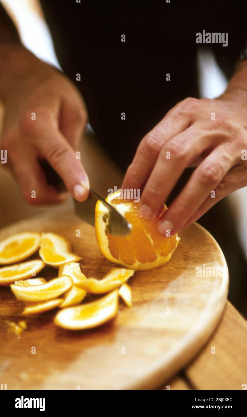 Removing pith from orange before slicing - Stock Photo
