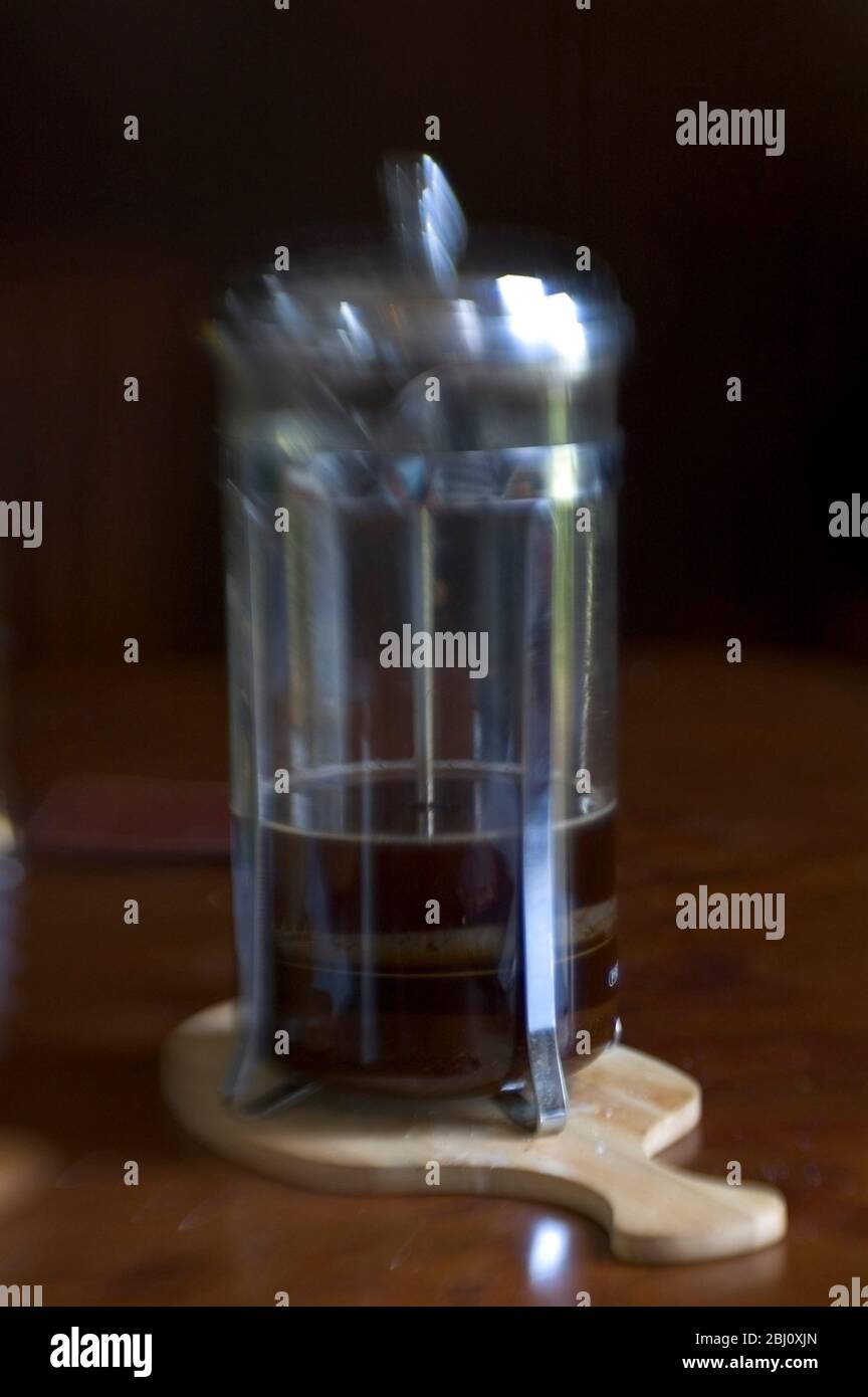 Blurred image of coffee pot on dark wooden surface with dark background . Shot with lensbabies lens - Stock Photo