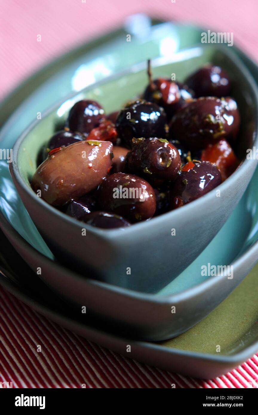 Rustic Italian black olives in bowl on stack of similar green and blue bowls - Stock Photo
