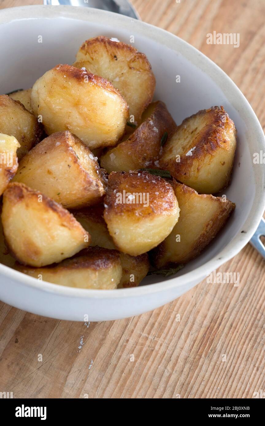White china bowl of roast potatoes - Stock Photo