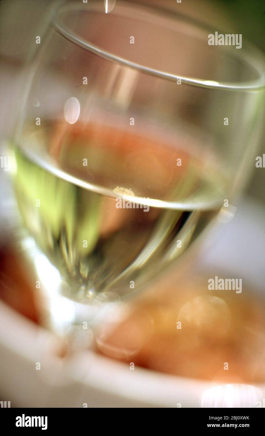 Glass of white wine against blurred coloured background - Stock Photo