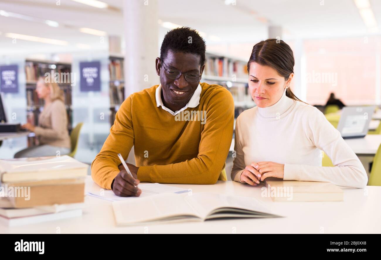 People reading and making notes while preparing for exam in library Stock Photo