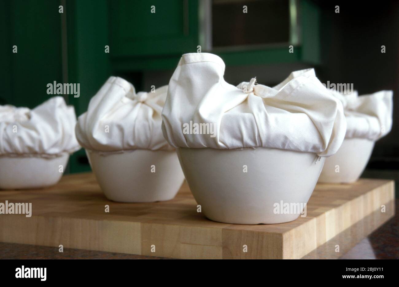 A batch of traditional English Christmas puddings, with cloths tied ready to steam - Stock Photo