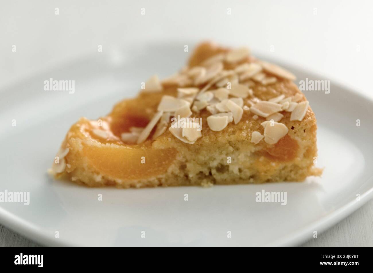 Slice of apricot cake on small white plate - Stock Photo
