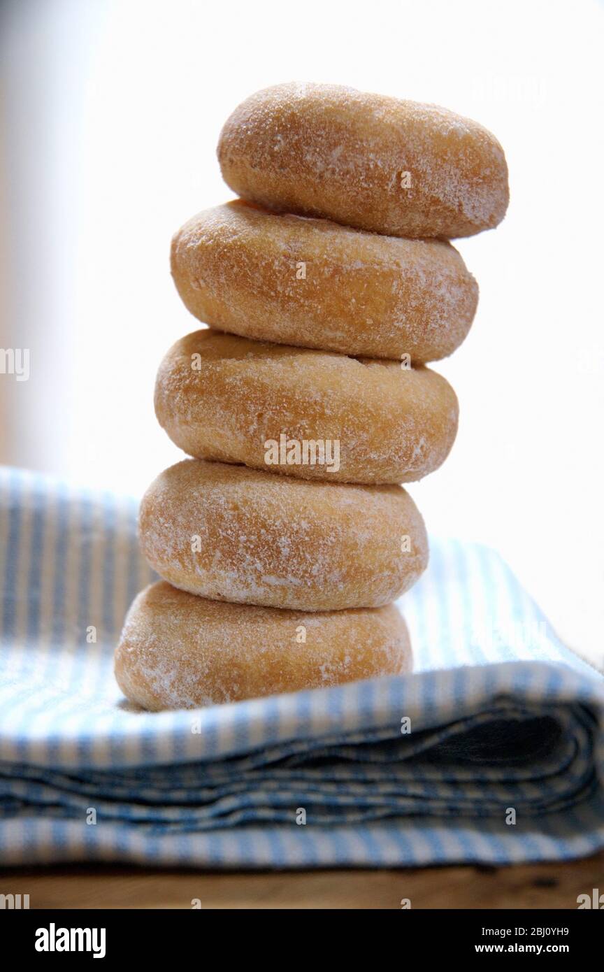 Mini ring doughnuts stacked on blue and white napkin - Stock Photo
