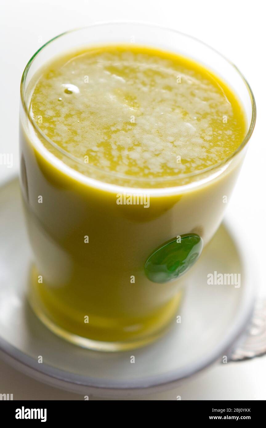 Smoothie made of kiwi fruit and orange juice blended with egg and honey - Stock Photo